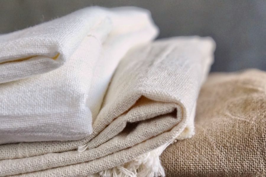 Photograph of natural, unbleached, organic fabrics, folded gently