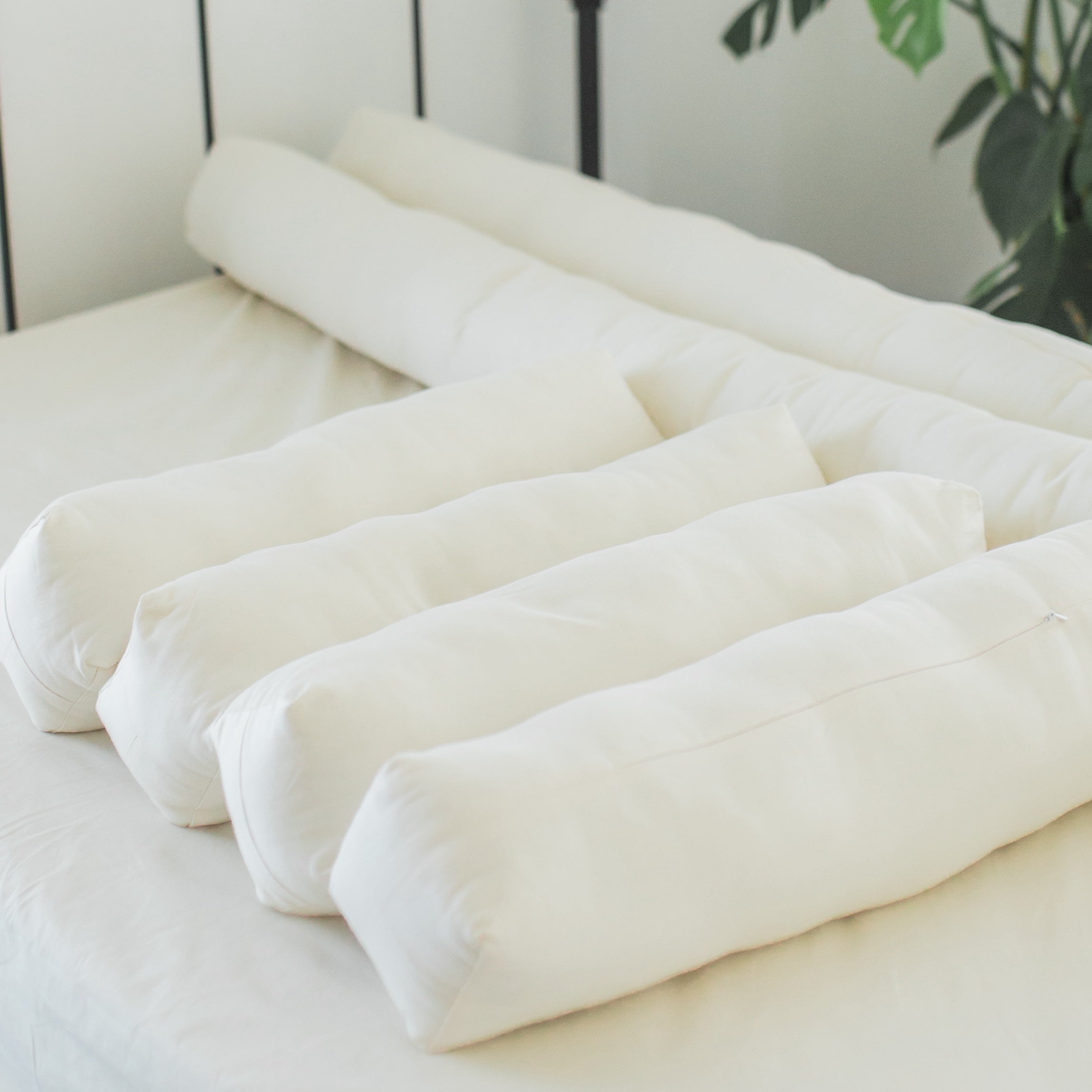 Oolie organic cotton bolster pillows in two different lengths, arranged on a bed.