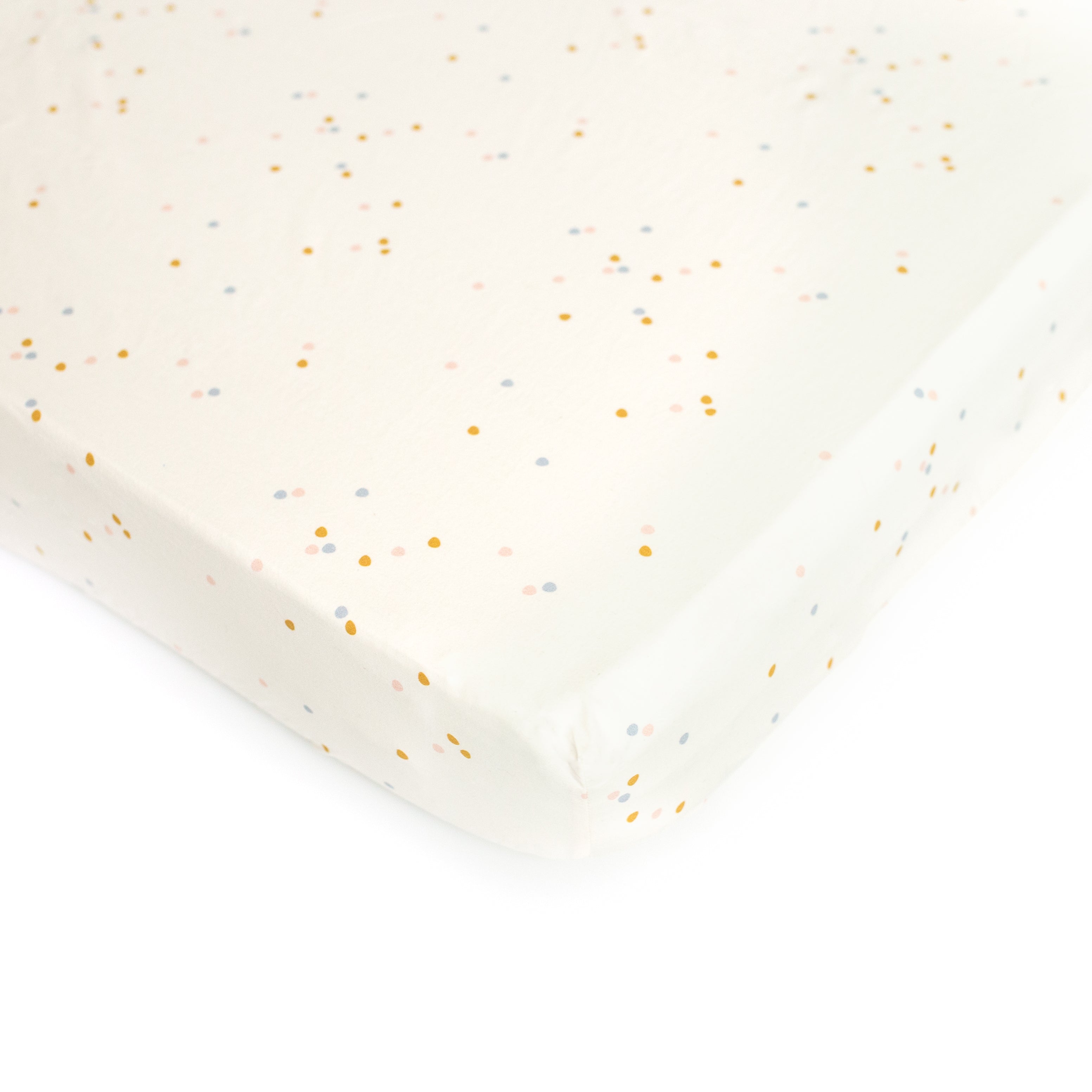 An Oolie organic cotton crib sheet with the cream confetti print, a natural color with small, irregular spots of color.