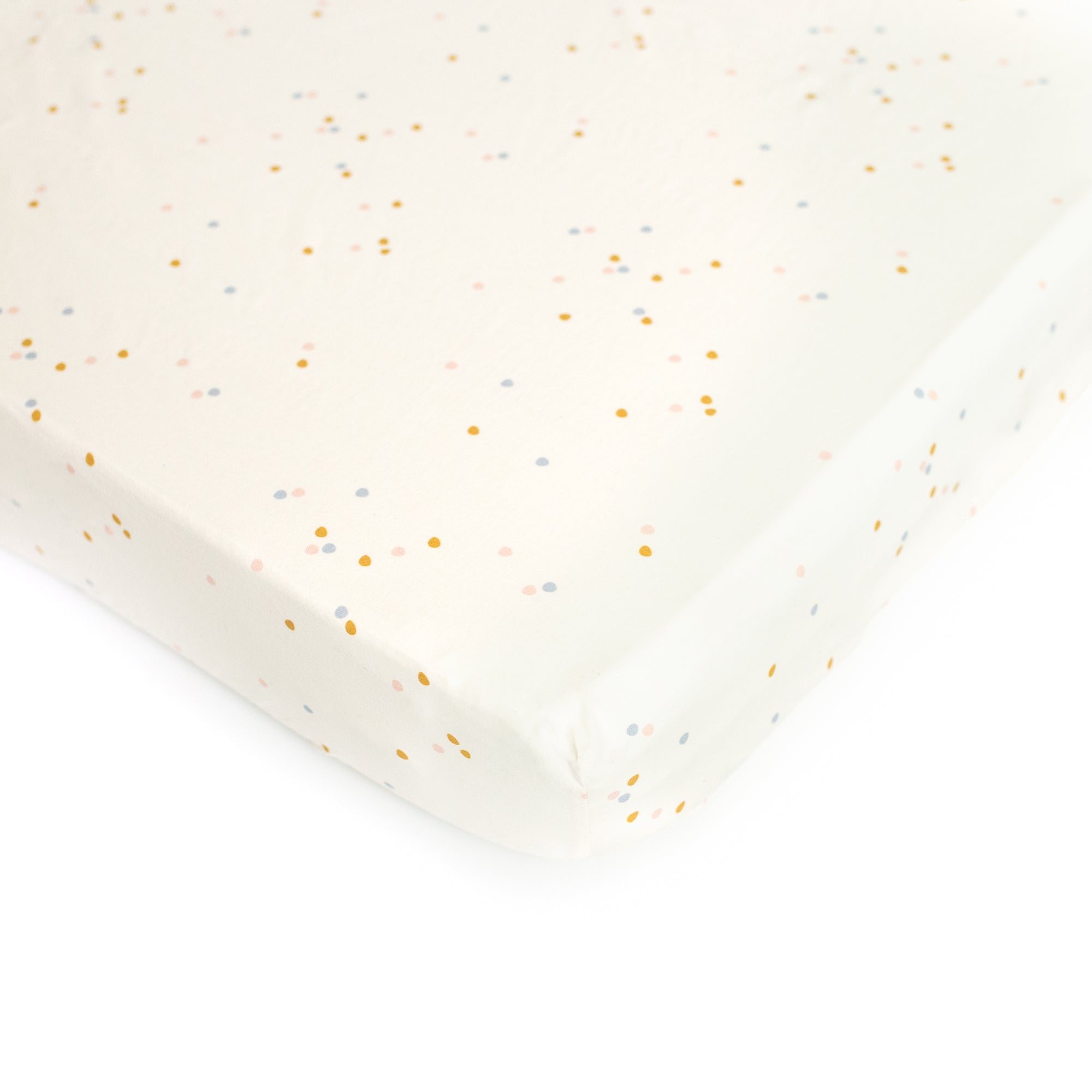 An Oolie organic cotton crib sheet with the cream confetti print, a natural color with small, irregular spots of color.