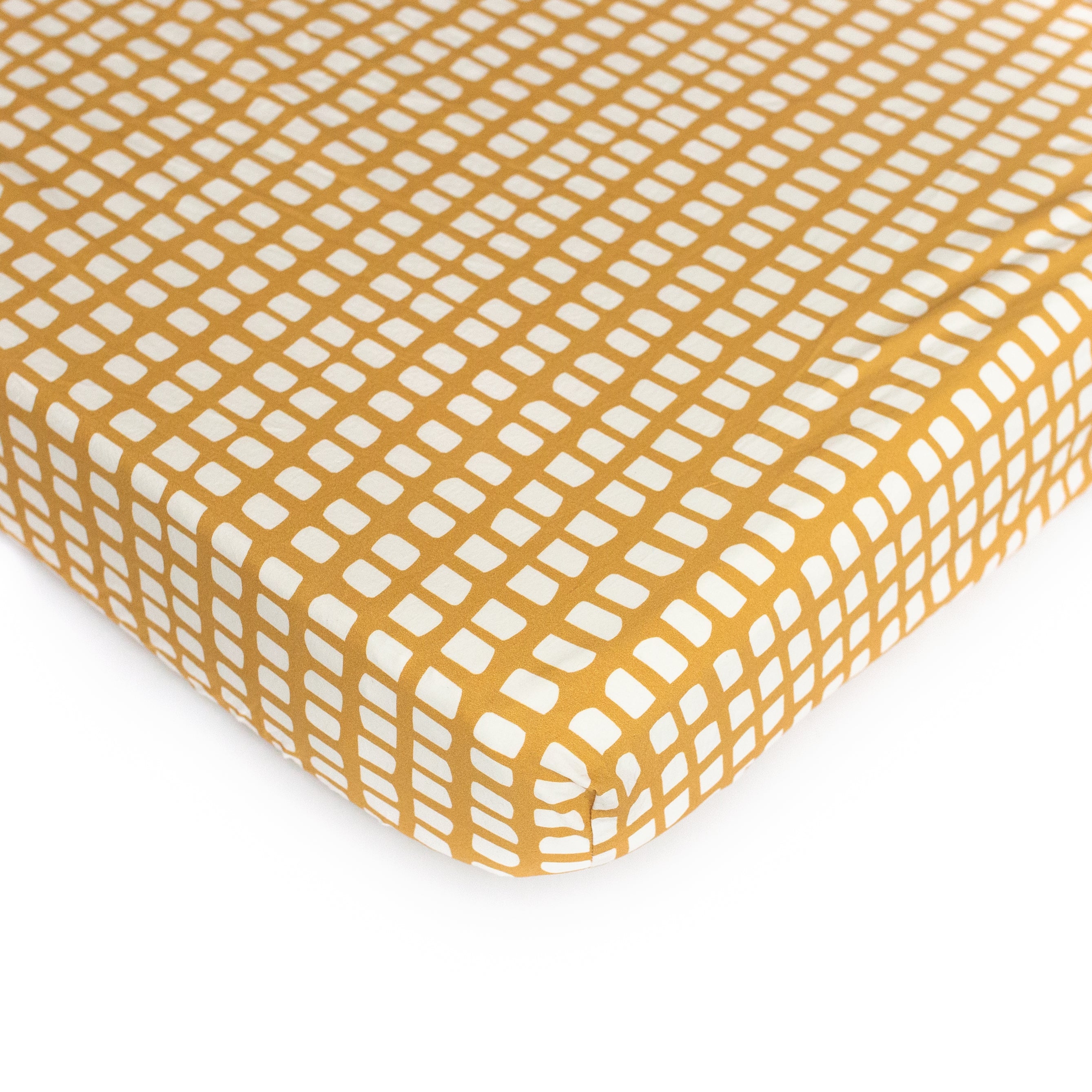 An Oolie organic cotton crib sheet with the picnic print, a deep gold with irregular panels in white.