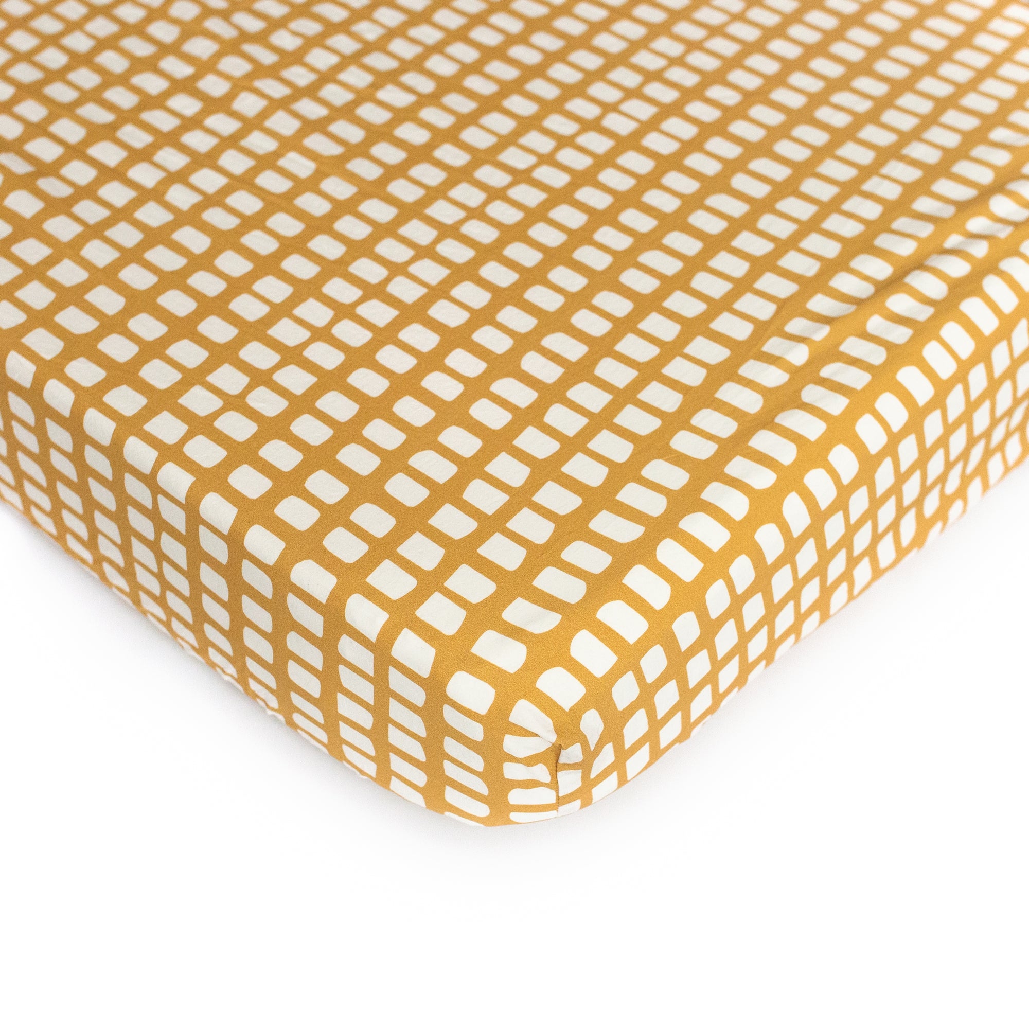 An Oolie organic cotton crib sheet with the picnic print, a deep gold with irregular panels in white.