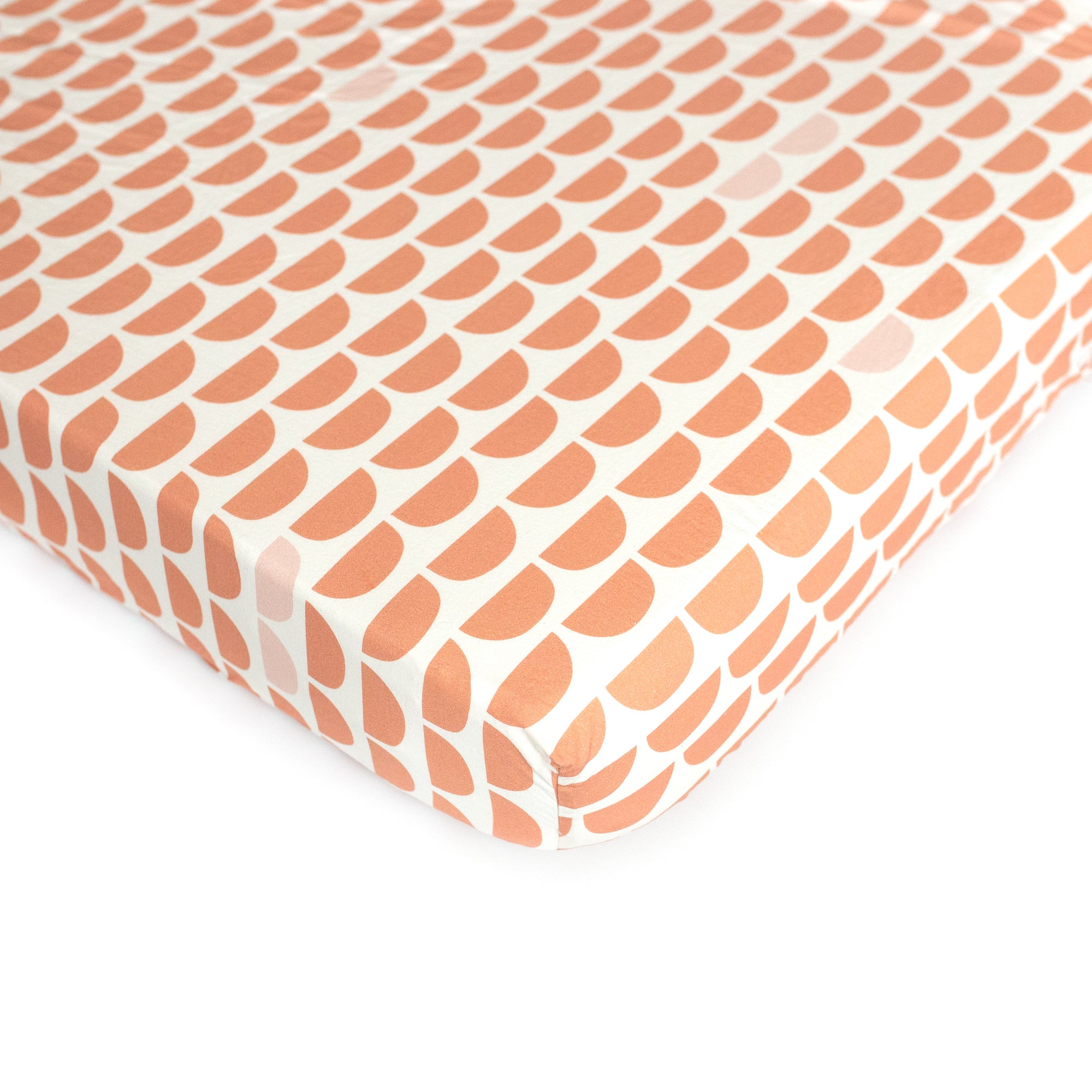 An Oolie organic cotton crib sheet with the red hills print, a natural color with a series of repeating red semicircles.