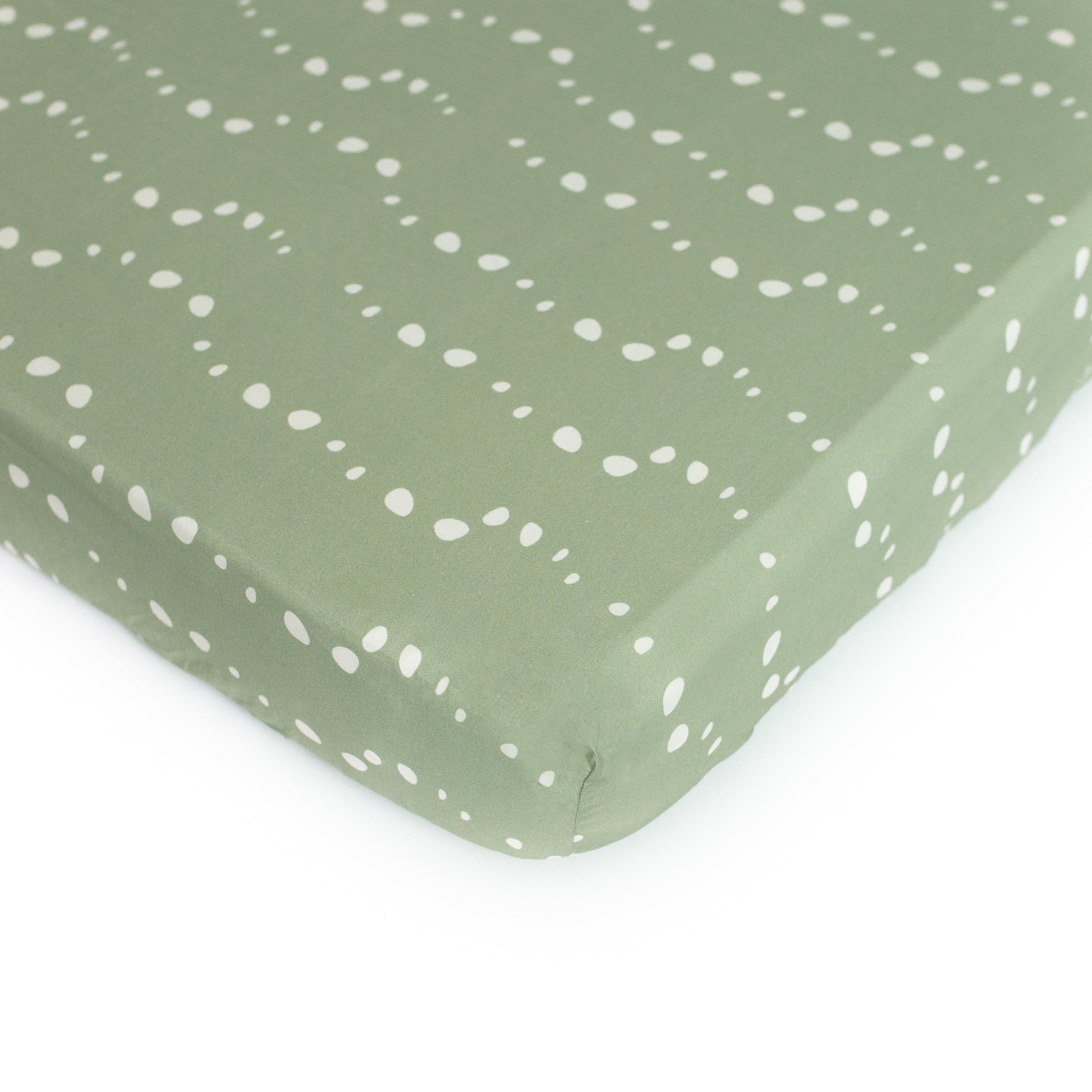 An Oolie organic cotton crib sheet with the sage stones print, a soft green color with white bubbles or irregular stone shapes.