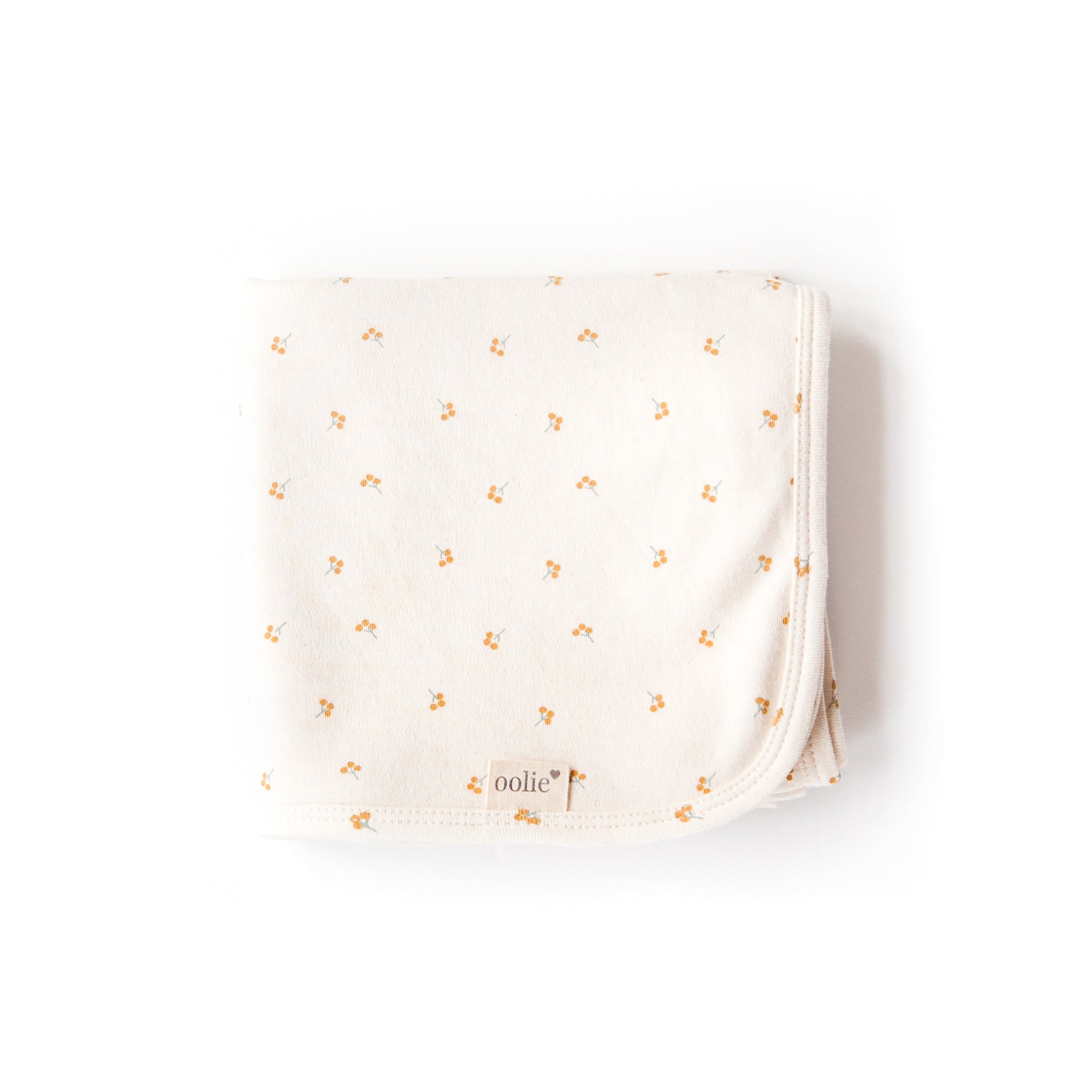 An Oolie organic cotton baby blanket with the gold sprig print, a natural color with small sprigs of golden berries.