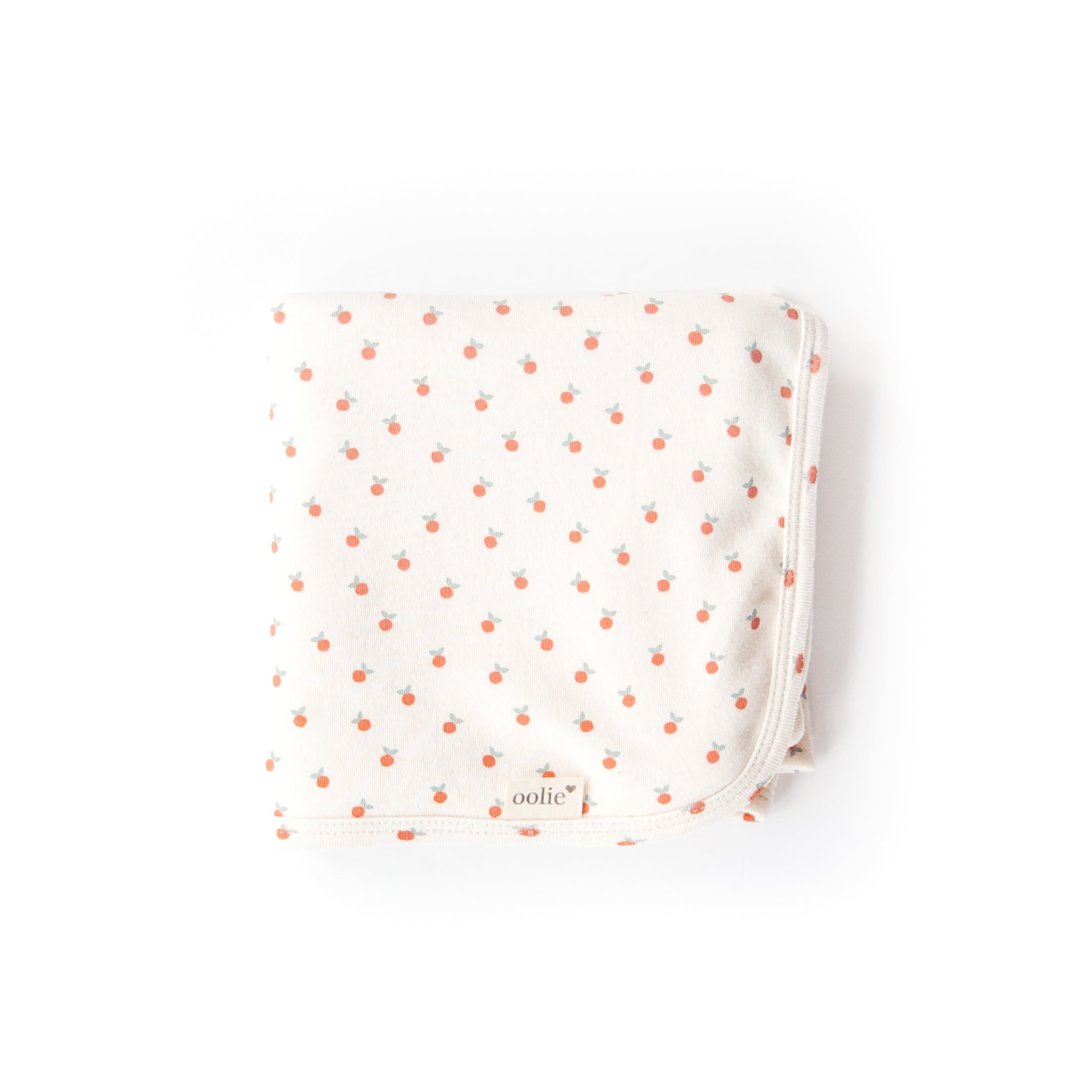 An Oolie organic cotton baby blanket with the little peach print, a natural color with tiny, irregular peaches in a repeating pattern.