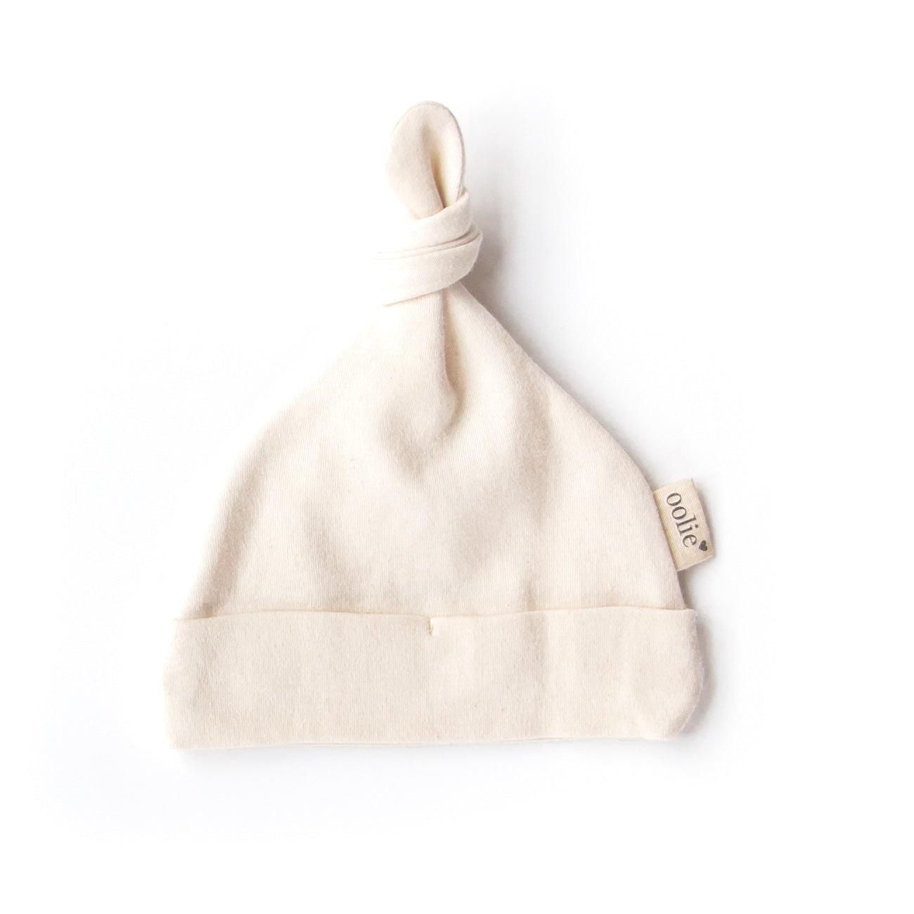 A natural Oolie organic cotton top knot baby hat, unprinted, revealing its natural, undyed, unbleached color.