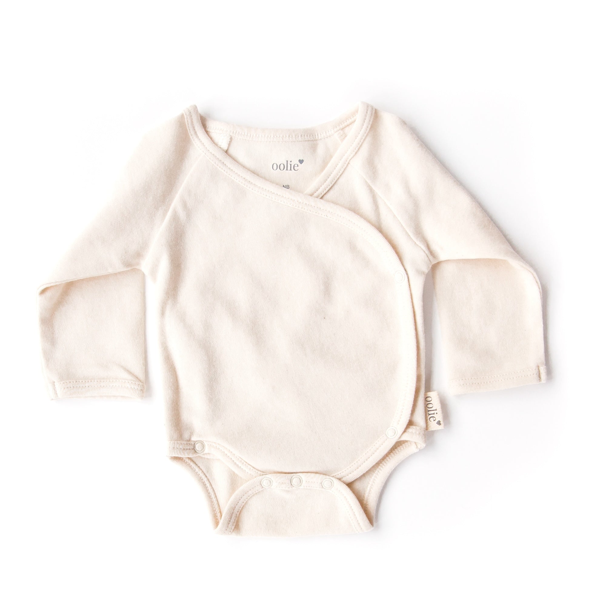 A natural Oolie organic cotton onesie, unprinted, revealing its natural, undyed, unbleached color.