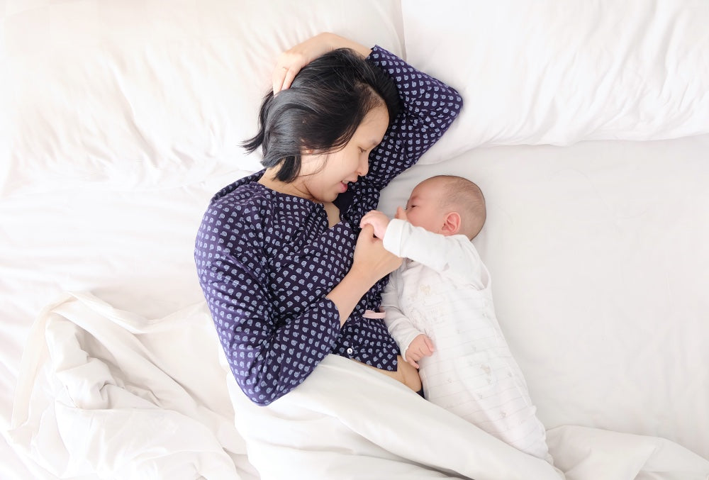 Mom with newborn snuggling in bed