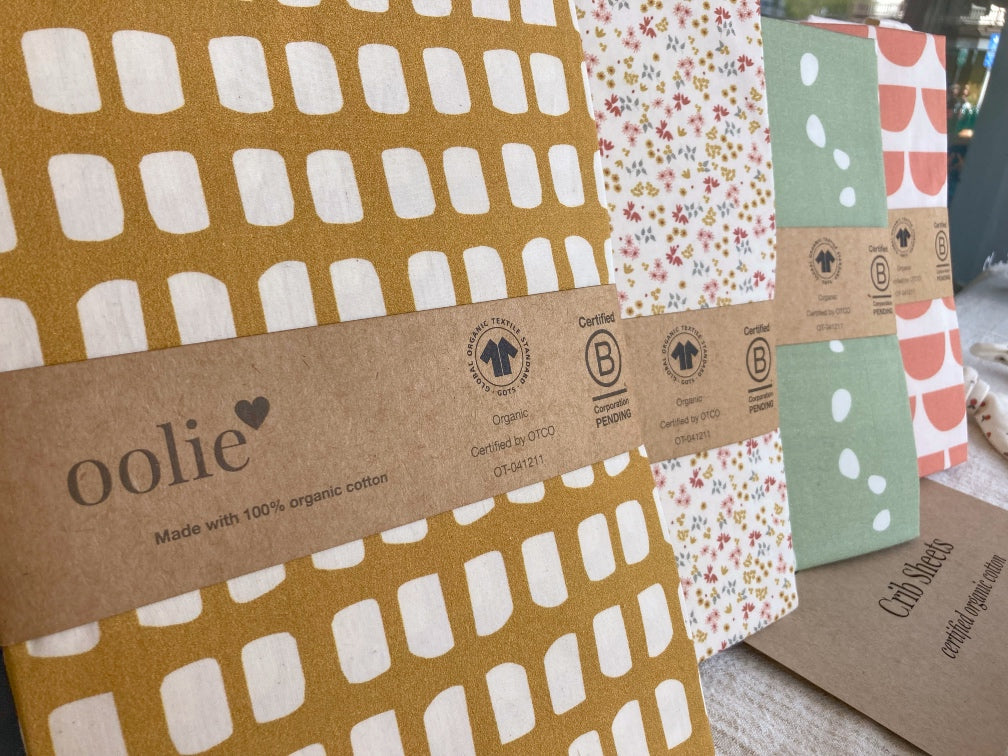 Oolie organic crib sheets with graphic prints displayed in front of Margaret O’Leary in Mill Valley