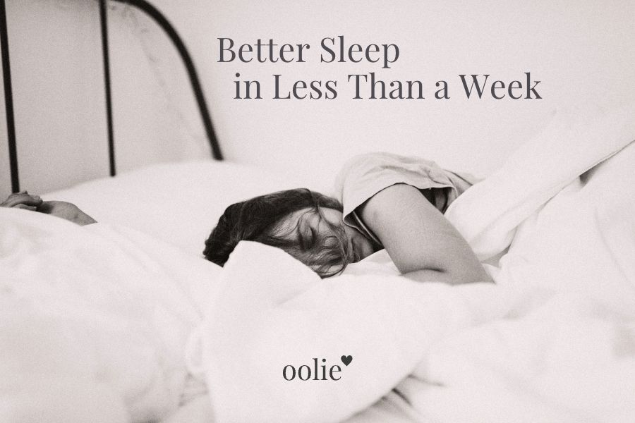 Photograph of a woman sleeping in bed, tucked into soft, white sheets, with the following text overlaid on the image: Better Sleep in Less Than a Week, and the Oolie logo with heart.