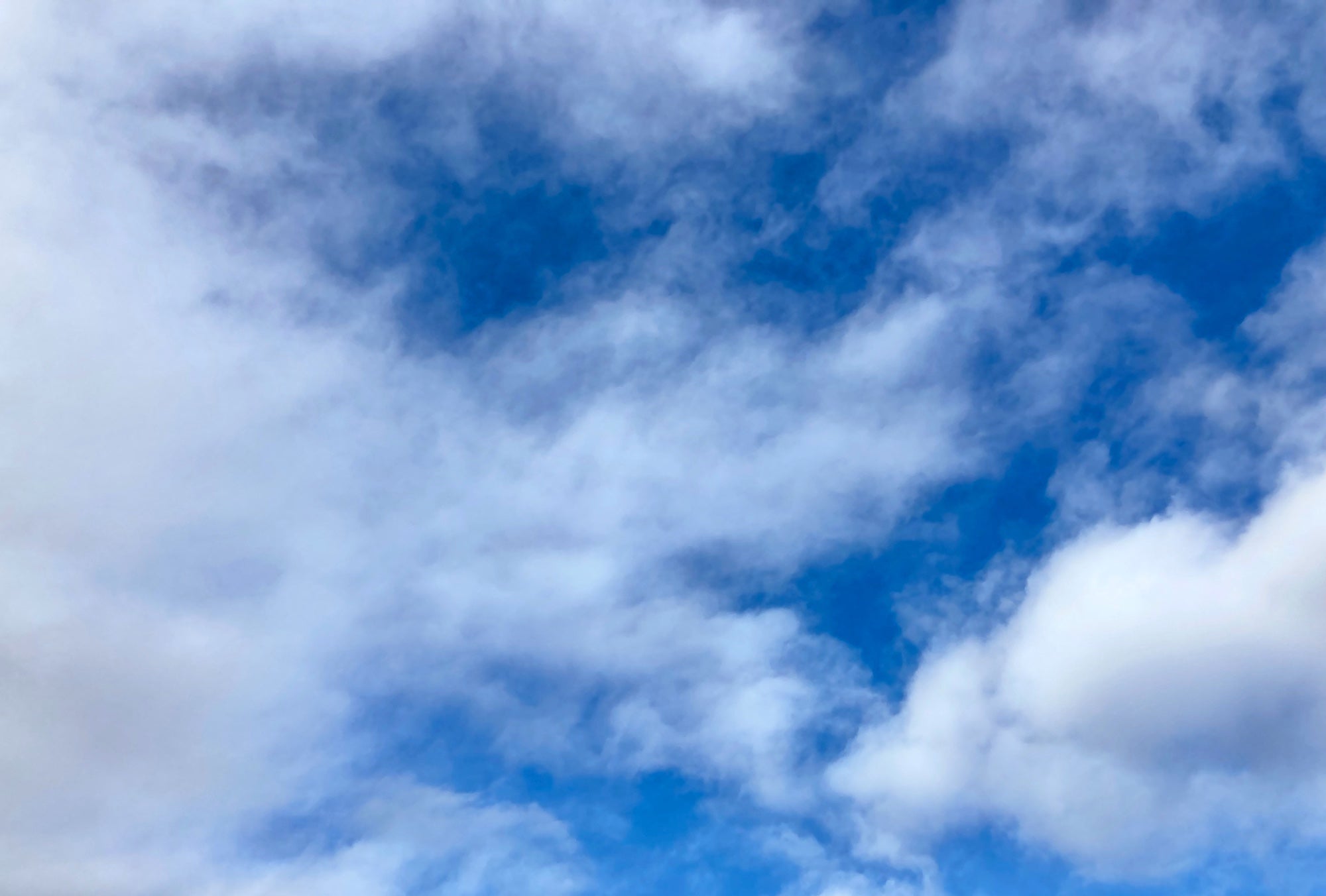 Fluffy white clouds curling against a deep blue sky