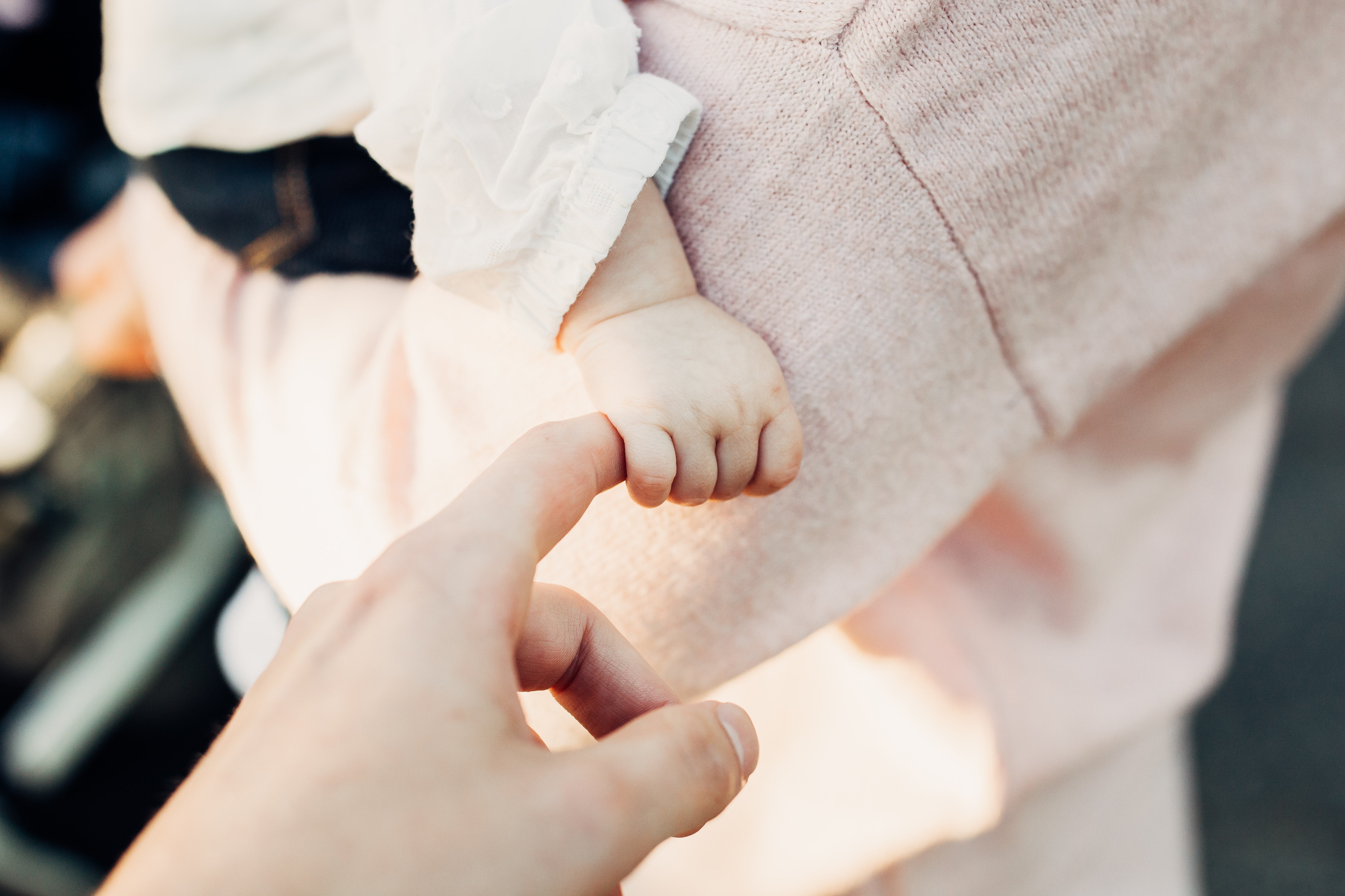 A baby's hand gently holding a grown-up's index finger.