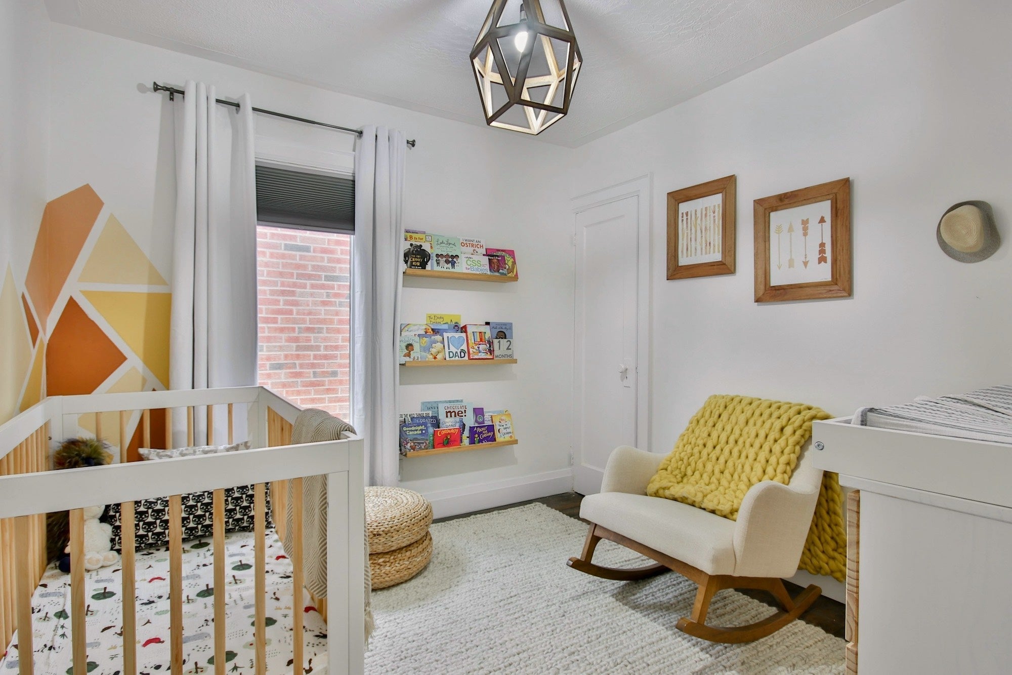 A baby’s nursery with crib, rocking chair, and changing table, in light, natural tones and a large window.