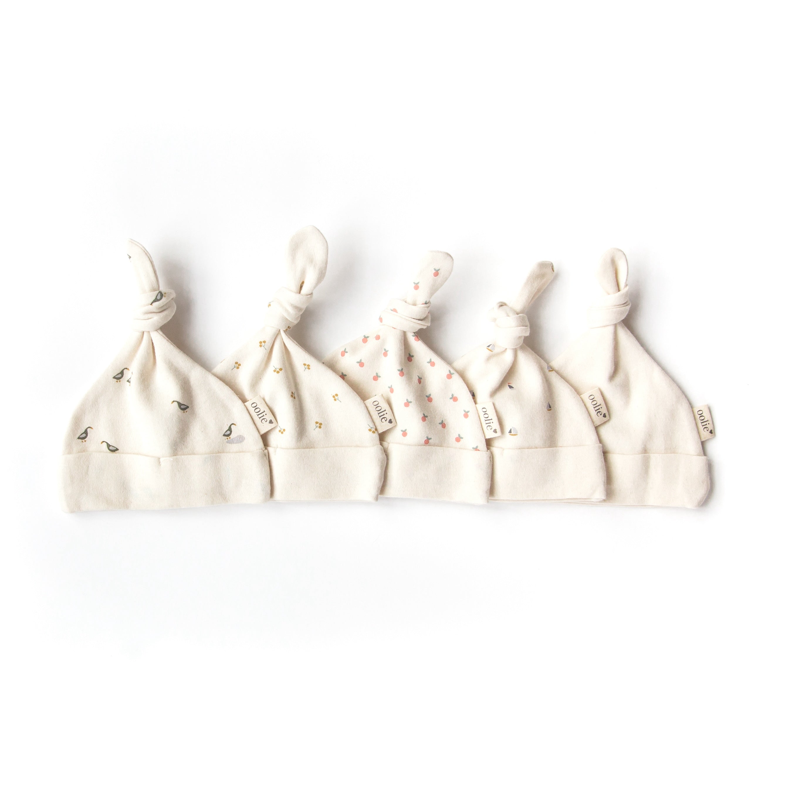Oolie organic top knot baby hats in five different graphic prints, gently set on a white background.