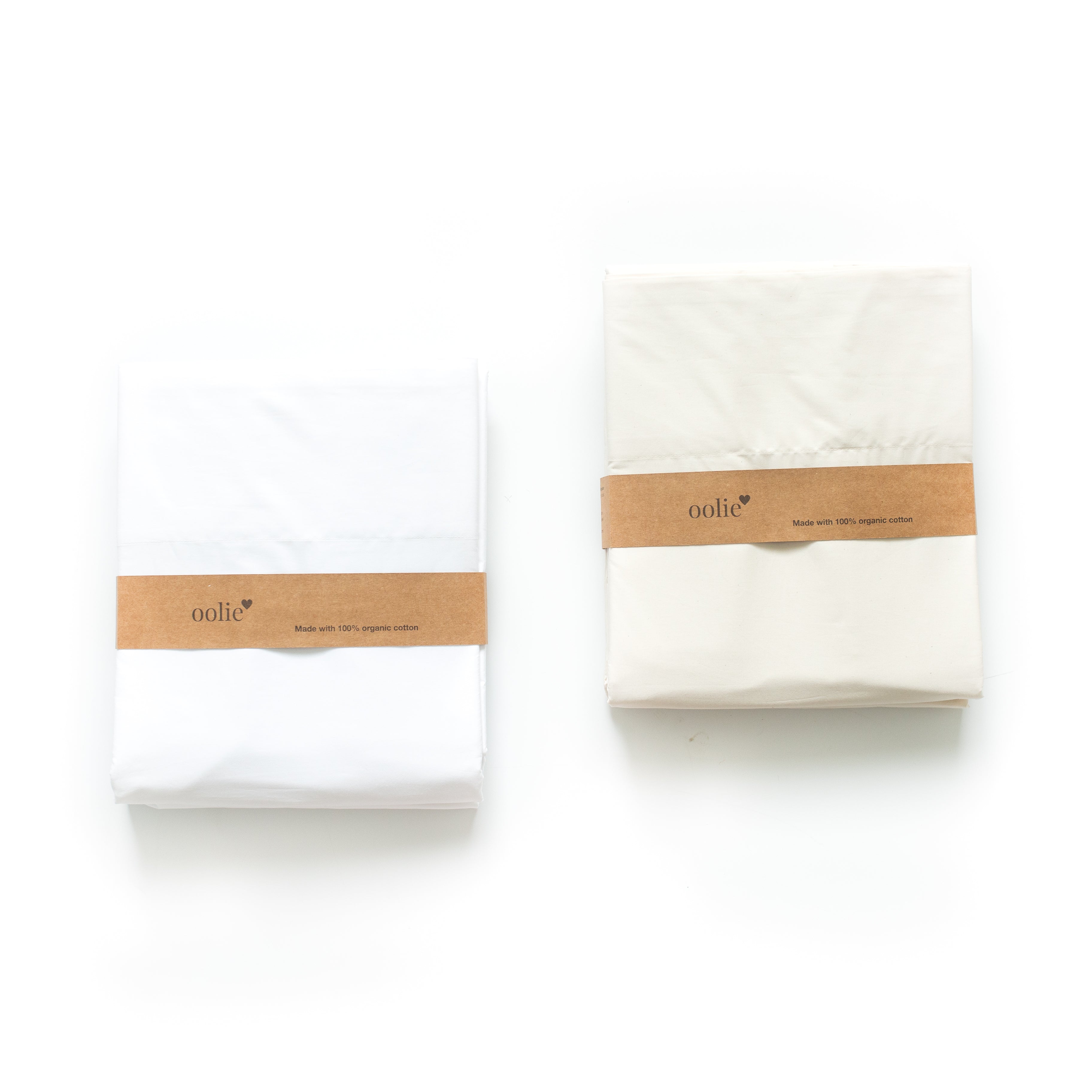 Two packaged Oolie organic cotton sheet sets on a white background. One sheet set is white, and the other is natural, unbleached cotton.