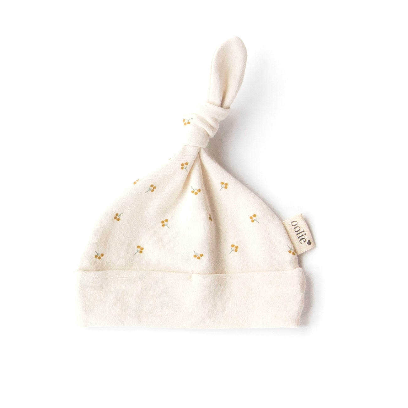 An Oolie organic cotton top knot baby hat with the gold sprig print, a natural color with small sprigs of golden berries.