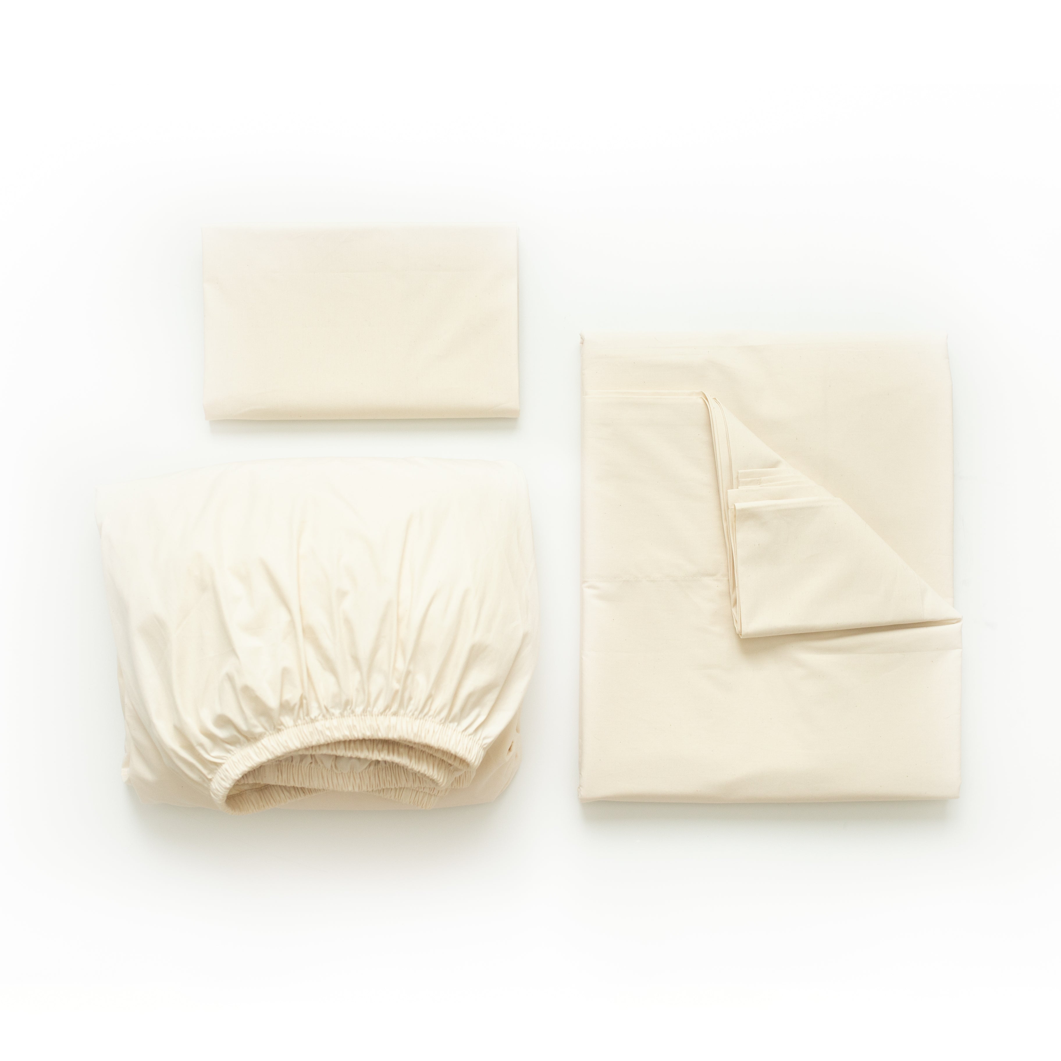 Oolie organic cotton pillowcases, flat sheet, and deep fitted sheet in natural, unbleached cotton, folded flat on a white background.