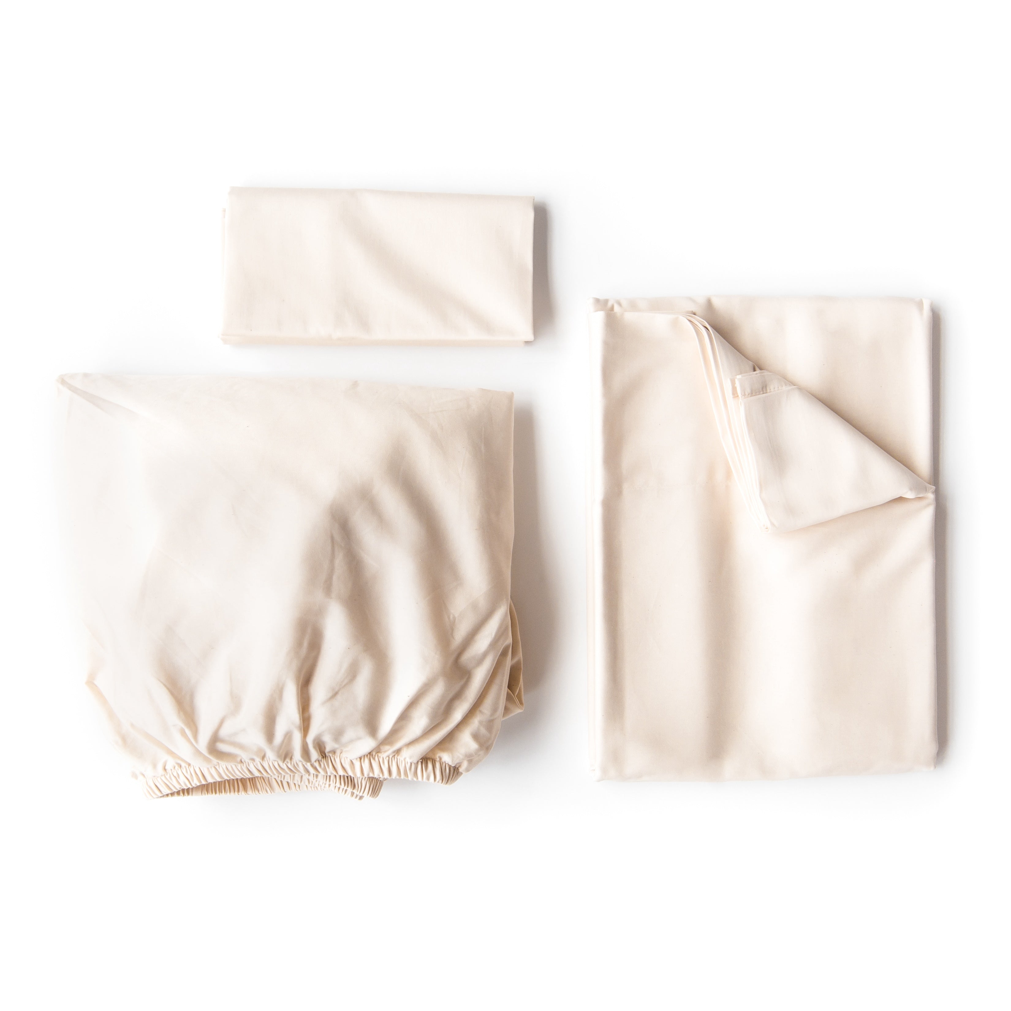 Oolie organic cotton pillowcases, flat sheet, and fitted sheet in natural, unbleached cotton, folded flat on a white background.