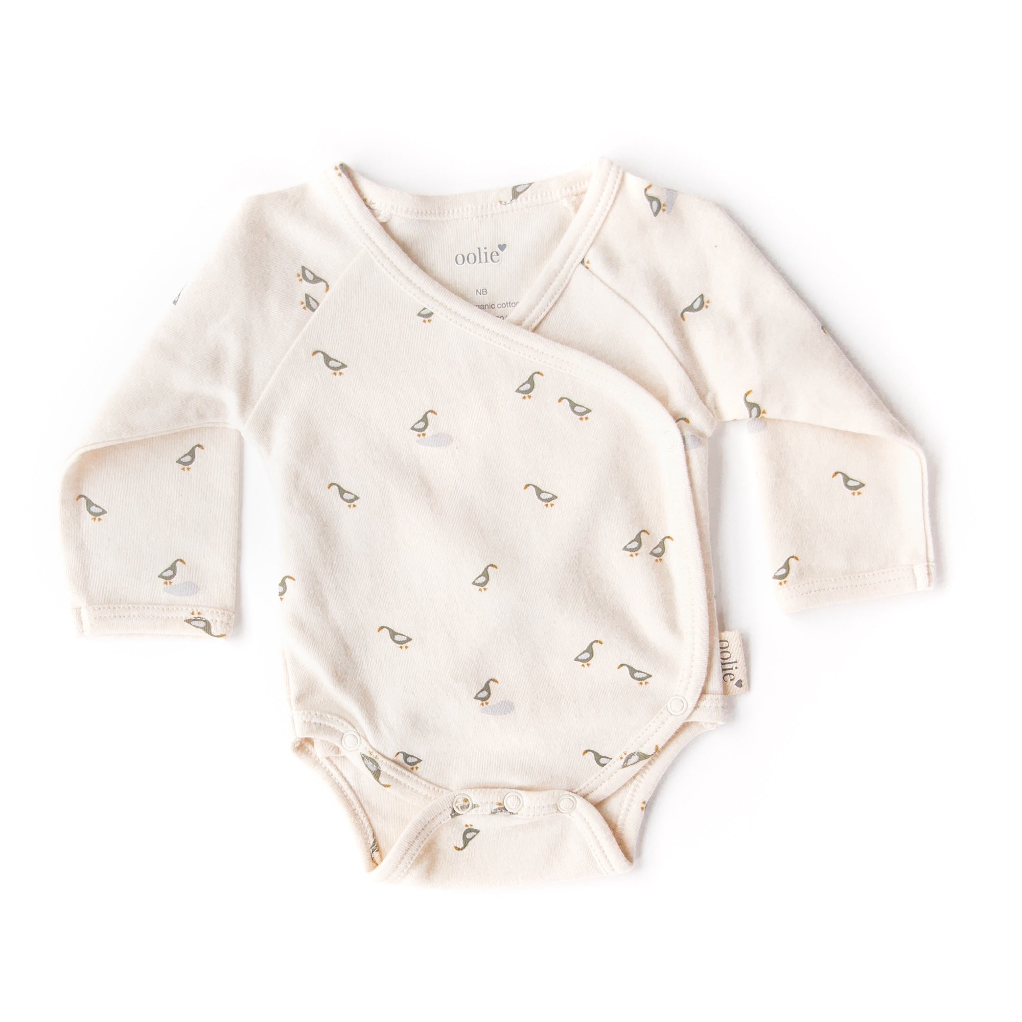 An Oolie organic cotton onesie with the runner ducks print, a natural color with small green and blue ducks in a repeating pattern.