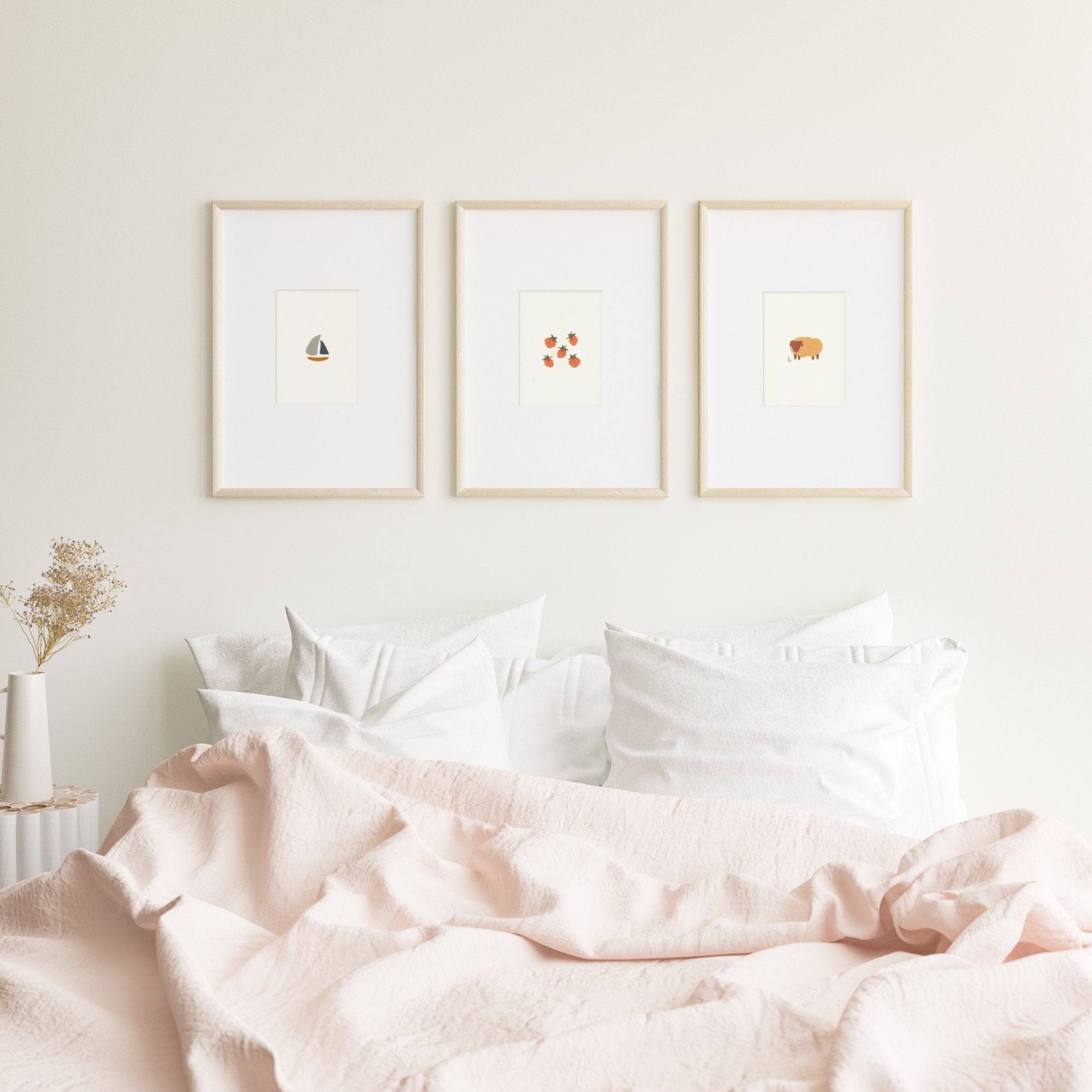 Three cute nursery prints framed and hanging on a wall over queen size bed. The prints show: a small sailboat, five strawberries, and a brown sheep.