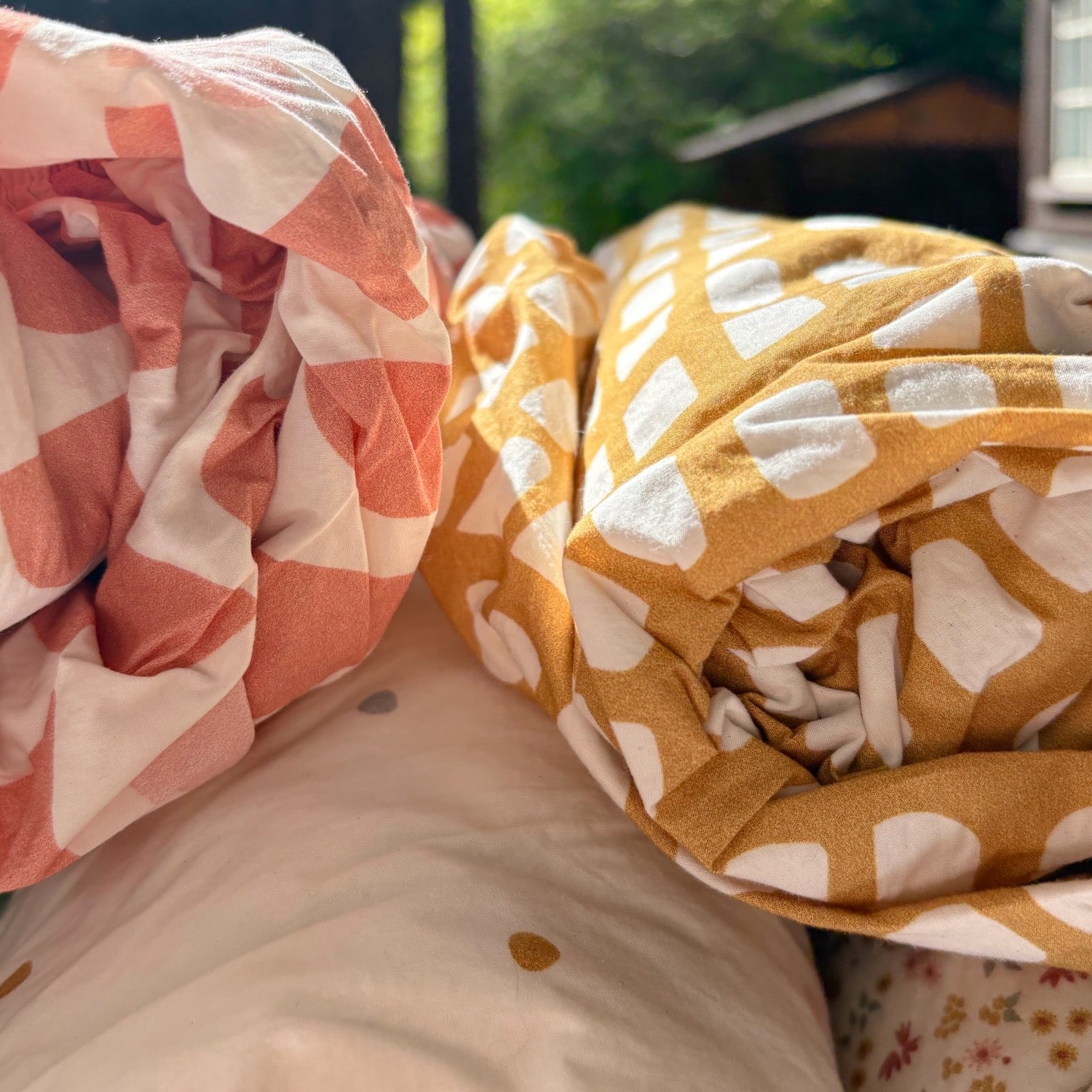 Stack of rolled up organic crib sheets with graphic prints