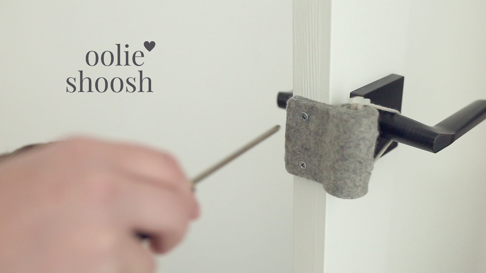 Video showing an adult installing an Oolie Shoosh with a Phillips screwdriver, then a young child closing his door and tugging on the Shoosh. Another adult demonstrates attempting to close the door with the Shoosh in Bumper Mode, but the door is prevented from closing. Then the Shoosh is shown installed in Silencing Mode, in which the door closes, but without a sound.